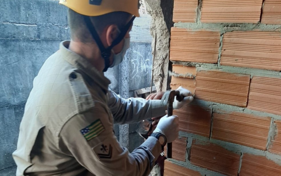 Bombeiros usam entalhadeira e martelo para retirar tijolos e libertar criança - (Foto: Reprodução/Corpo de Bombeiros)