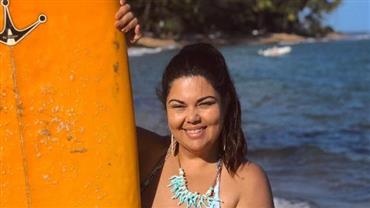 Aos 44 anos, Fabiana Karla posa com maiô decotado e prancha em praia